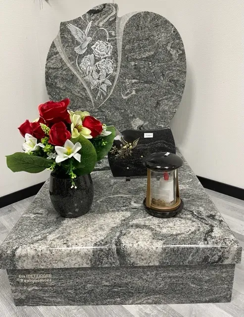 Monument funéraire en granit sculpté d'une colombe et de roses avec vase de fleurs.