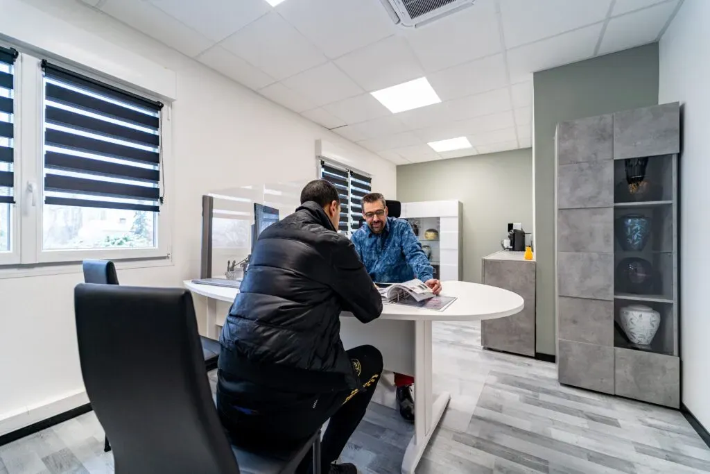 Conseiller funéraire recevant un client à un bureau dans une agence de pompes funèbres.