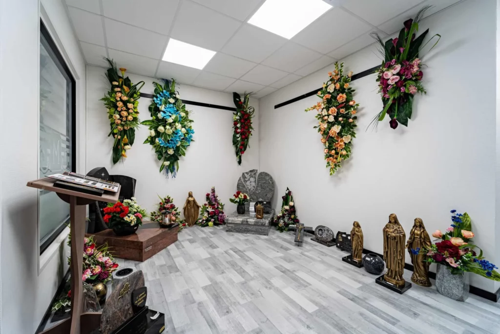 Exposition de stèles en granit et de compositions florales murales dans un espace funéraire.