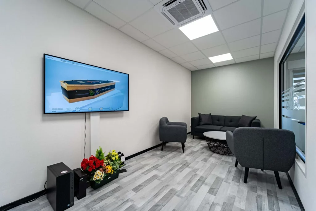 Salon d'accueil moderne avec écran de présentation et fauteuils pour les familles.